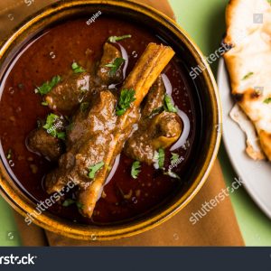 A bowl of stew with bread on the side.