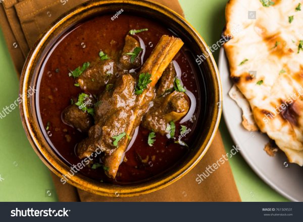 A bowl of stew with bread on the side.