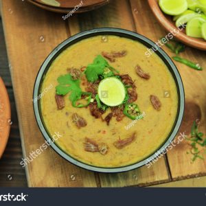 A bowl of soup with meat and vegetables on top.