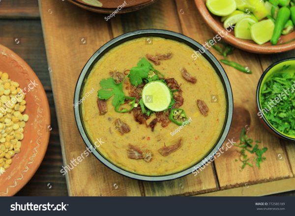 A bowl of soup with meat and vegetables on top.